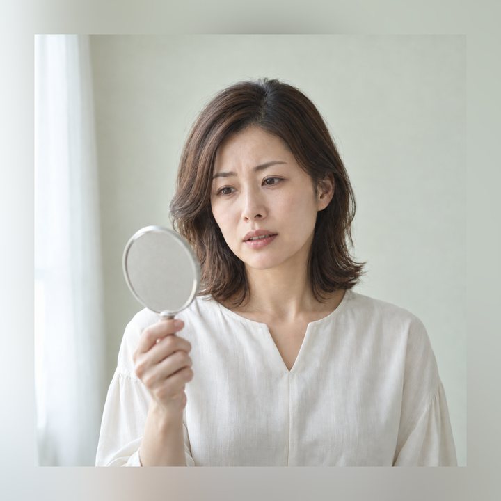 手鏡で前歯の色を確かめている女性
