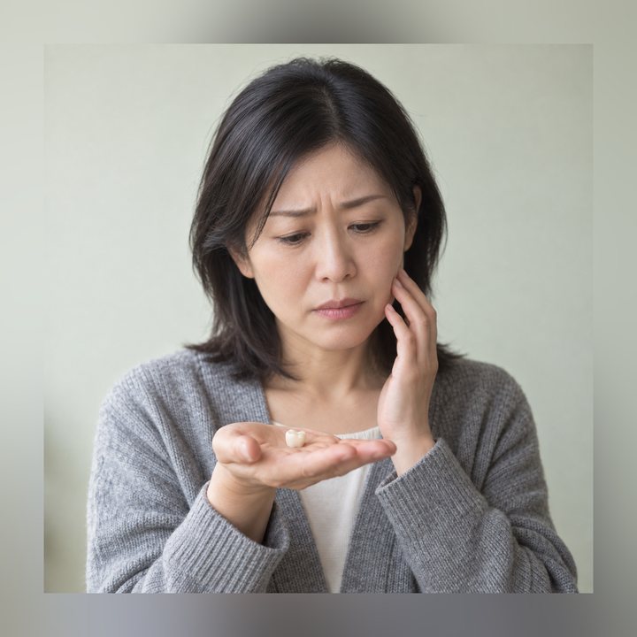 外れた被せ物を手のひらに乗せて困っている女性
